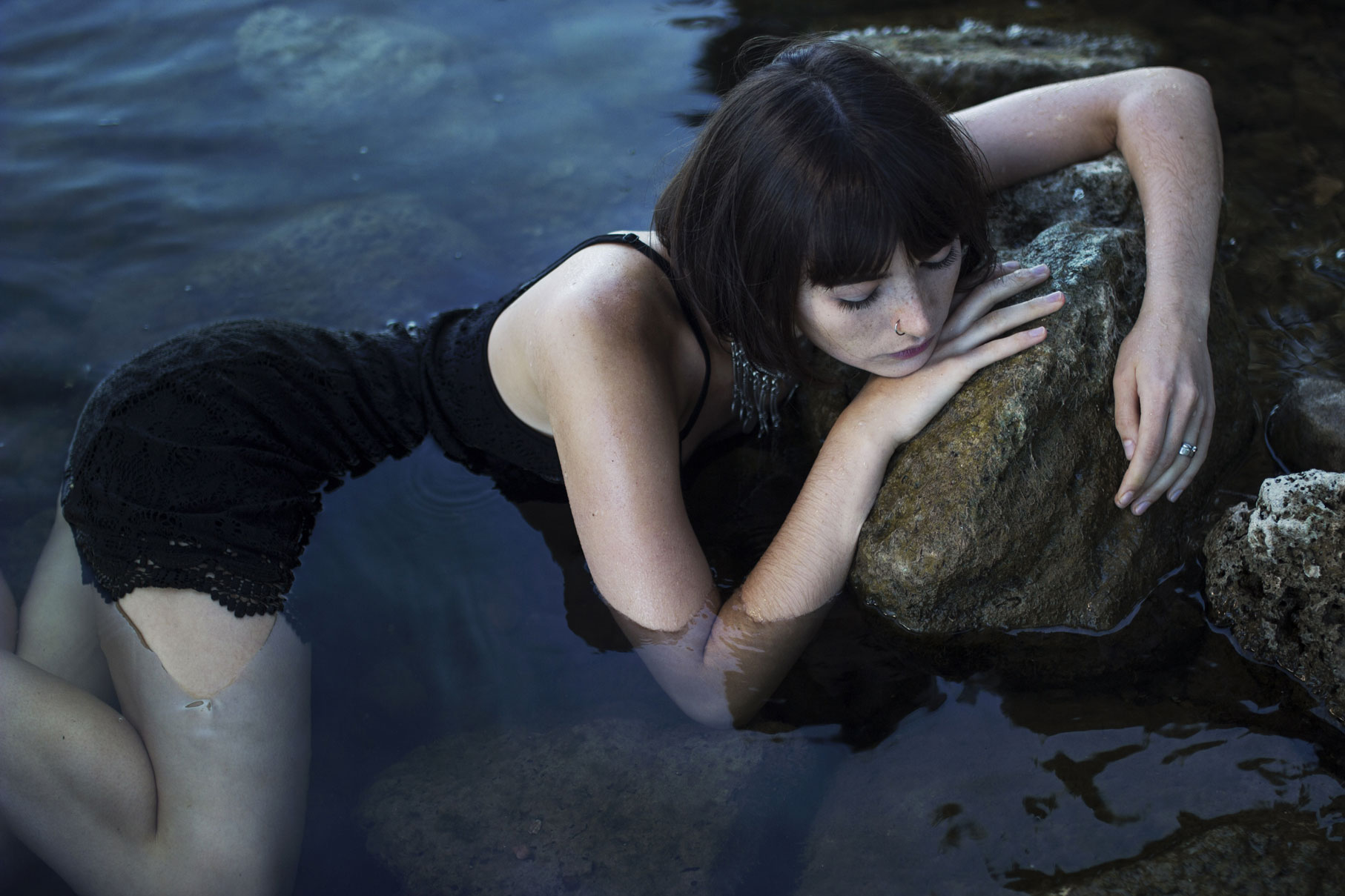 Jeune femme aux cheveux au carré dans l'eau d'un fleuve avec des rochers