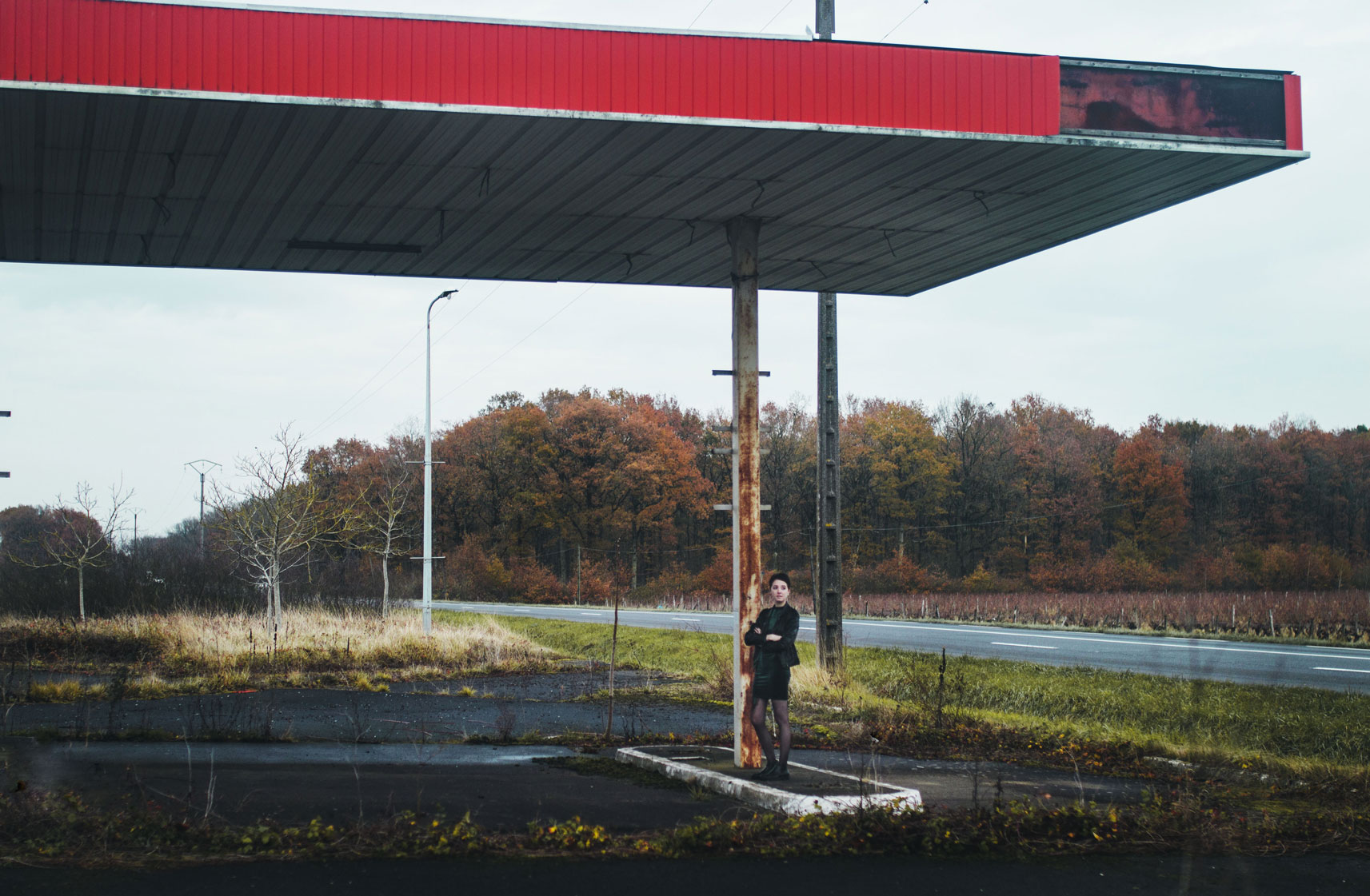portrait d'une jeune femme aux cheveux courts à tours dans une station essence abandonnée