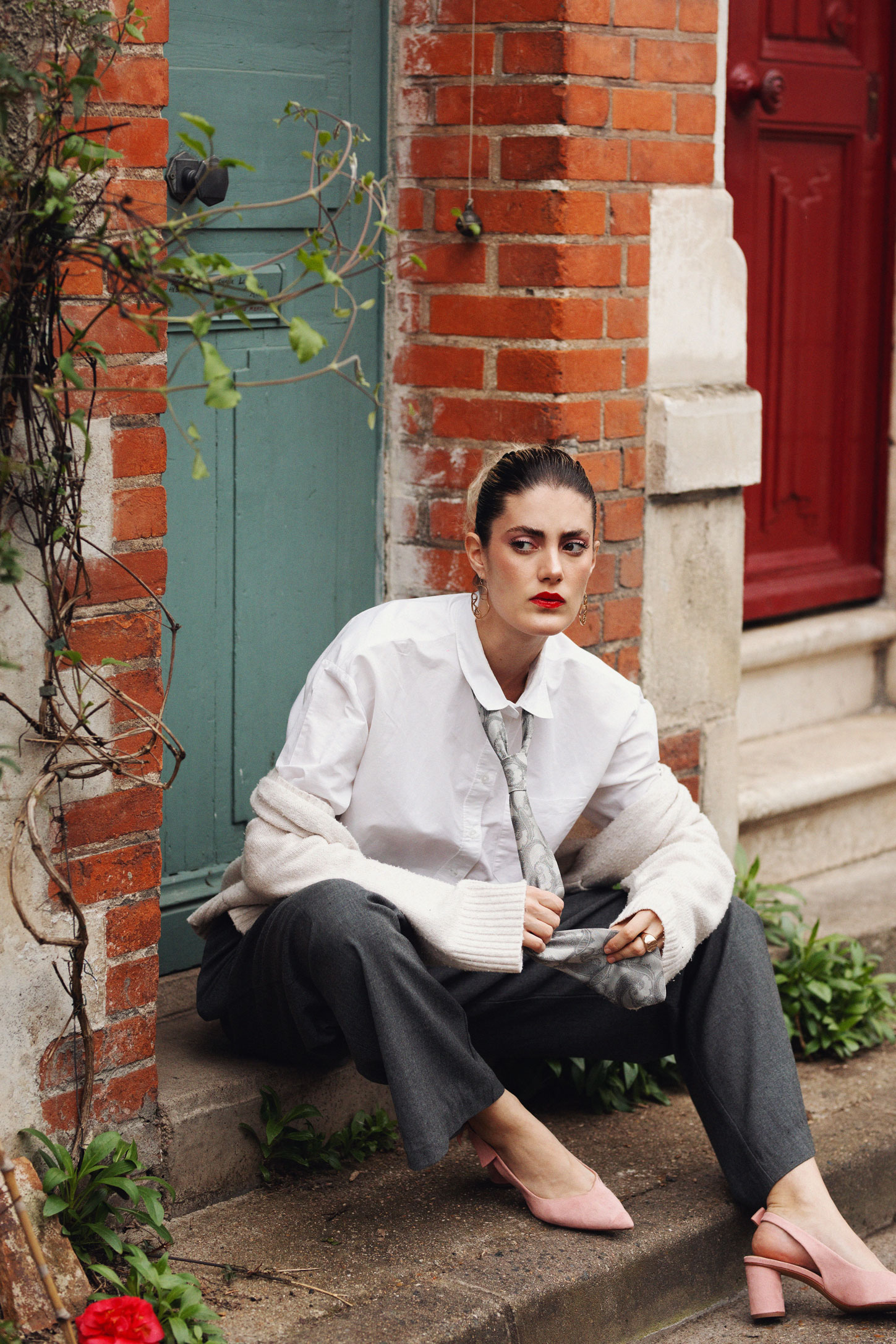 Jeune femme assise devant une façade de maison