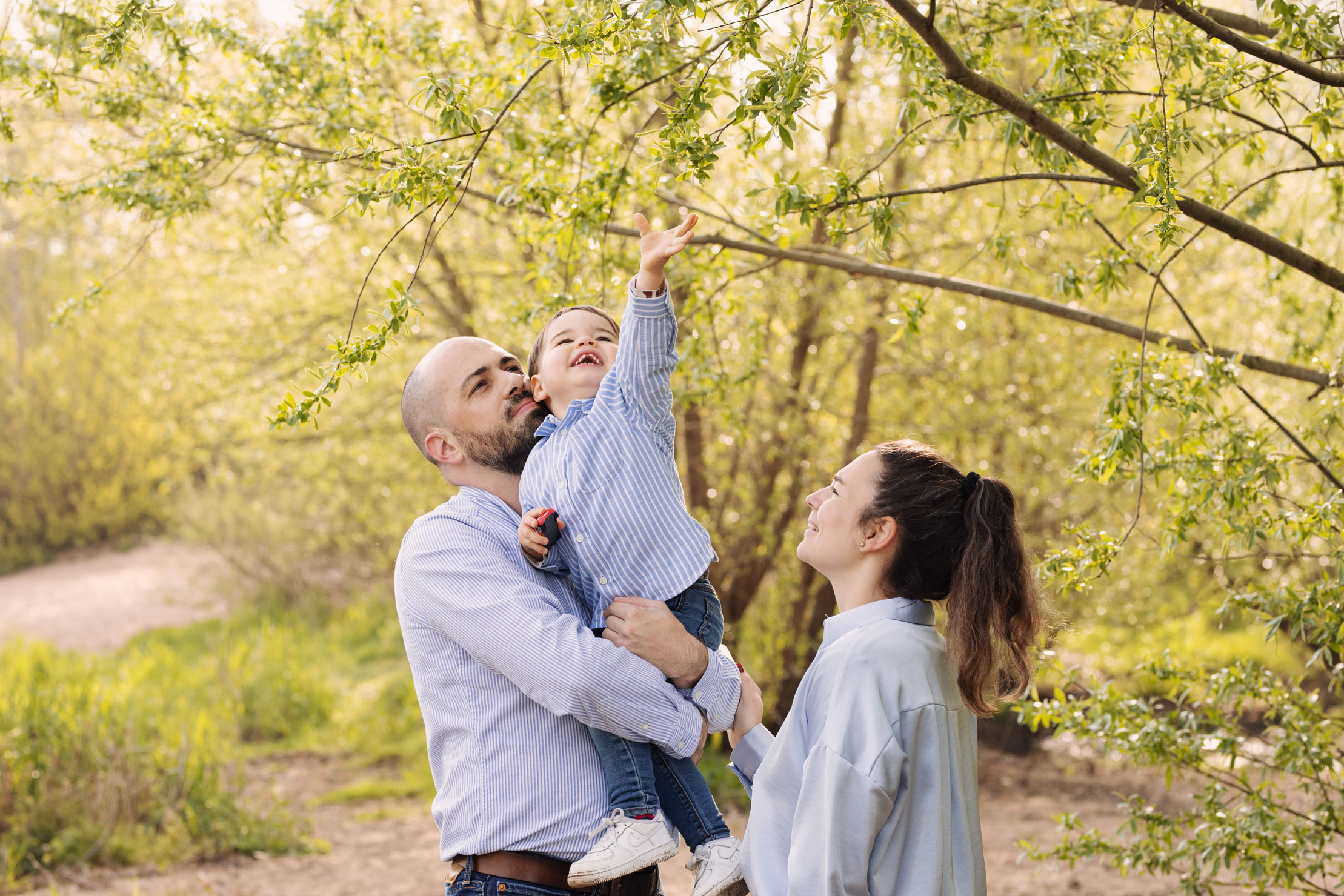 Photo d'une famille avec un petit garçon qui attrape une branche
